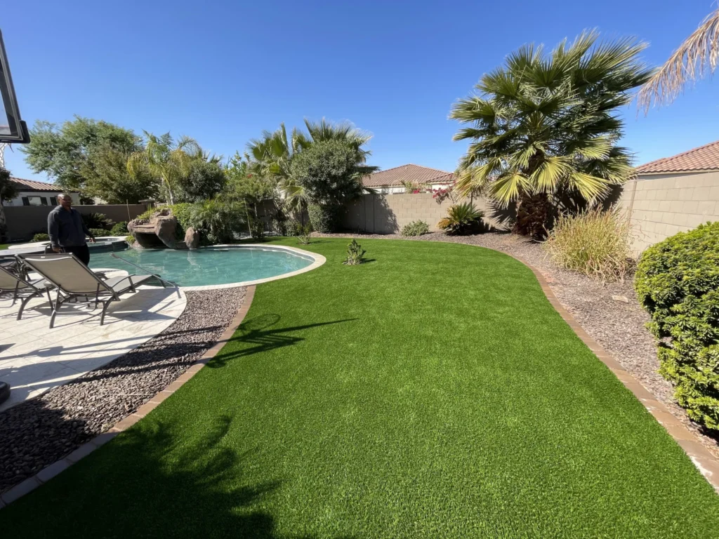 A backyard oasis featuring a pool encircled by a stylish patio with comfy lounge chairs. Artificial grass surrounds the pool and pavers. At a home in Chandler Arizona