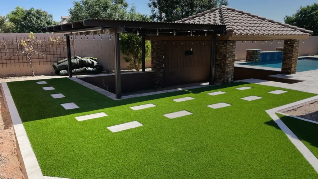 The image showcases a backyard oasis in one of the areas served, featuring a covered patio with a tiled roof and stone pillars. To the right, there's a modern pool beside a grassy lawn and stepping-stone pathway, framed by trees and a brick wall.